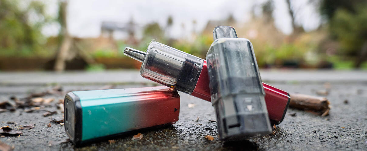 Wiederaufladbare Vapes liegen draußen auf dem Asphalt.