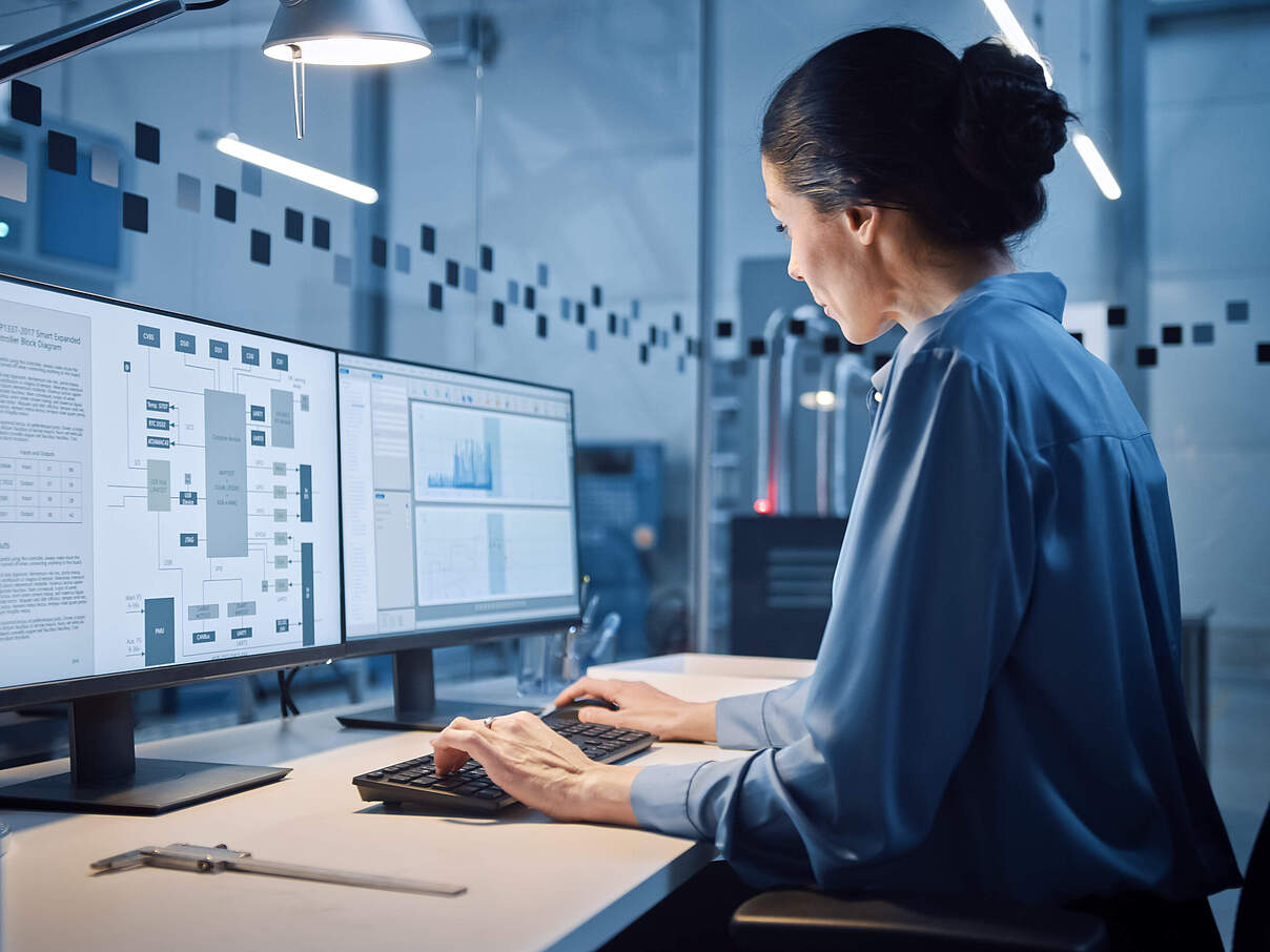 Factory Office: Portrait of Beautiful and Confident Female Industrial Engineer Working on Computer, on Screen Industrial Electronics Design Software. High Tech Facility with CNC Machinery