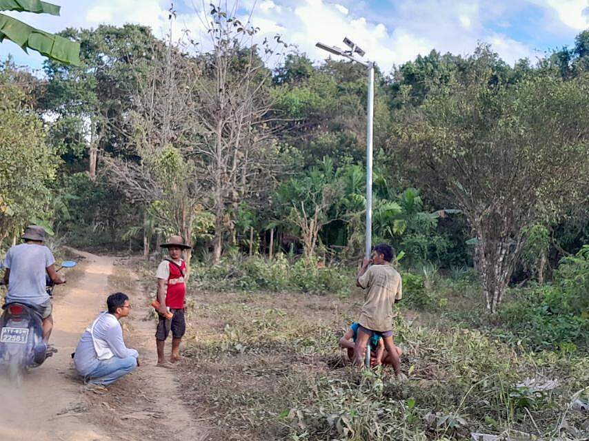 Mehrere Männer stellen eine Straßenlaterne in der Wildnis Myanmars auf.