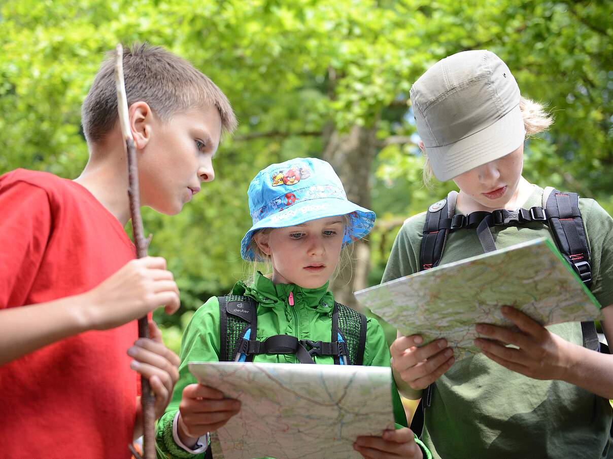 Kinder mit Karte und Rucksack im Wald