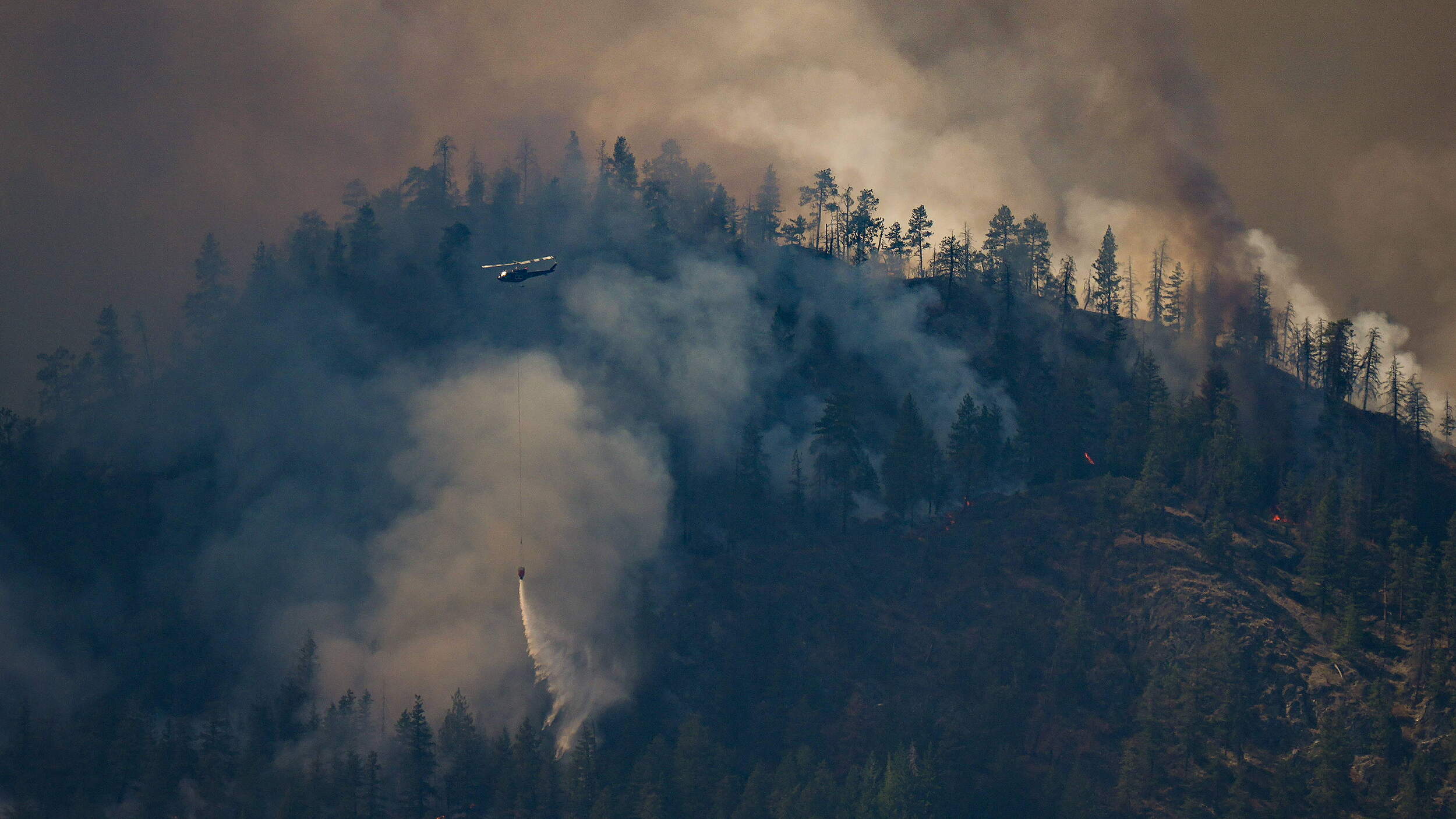 Ein Hubschrauber wird eingesetzt, um Wasser auf den Waldbrand am Quilpituk Creek abzuwerfen