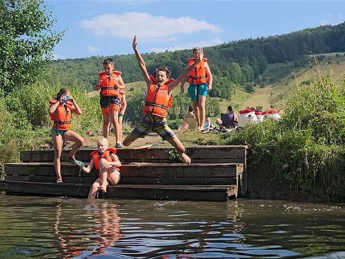 Das neue Ferienprogramm für die Junior Camps 2026 ist da. Kinder springen in den See.