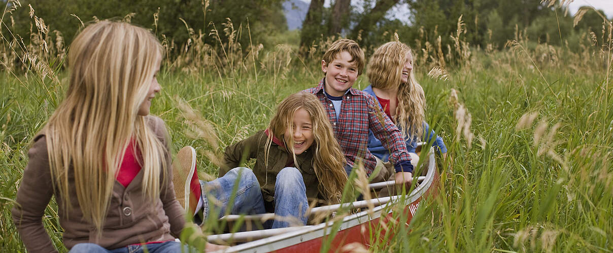 Kinder in einem Boot auf einer Wiese 
