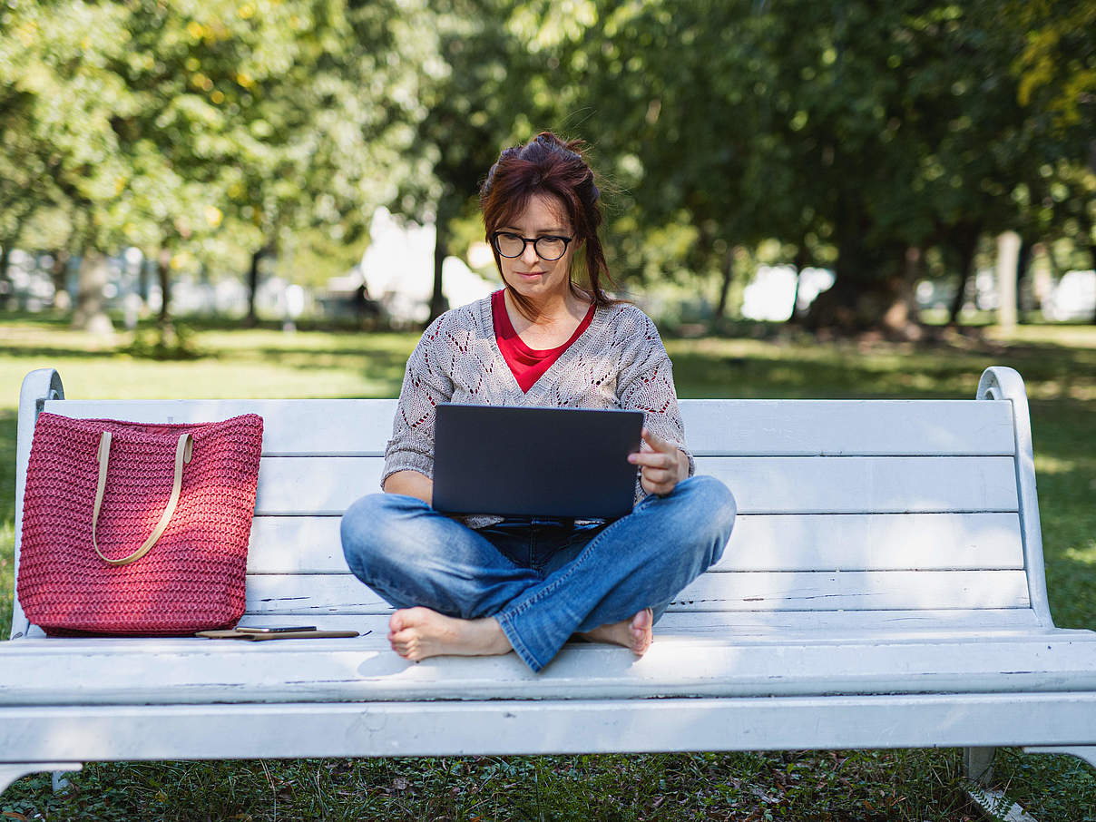 Eine Frau sitzt mit einem Laptop auf einer Bank © Jozef Polc / 500px / Getty Images