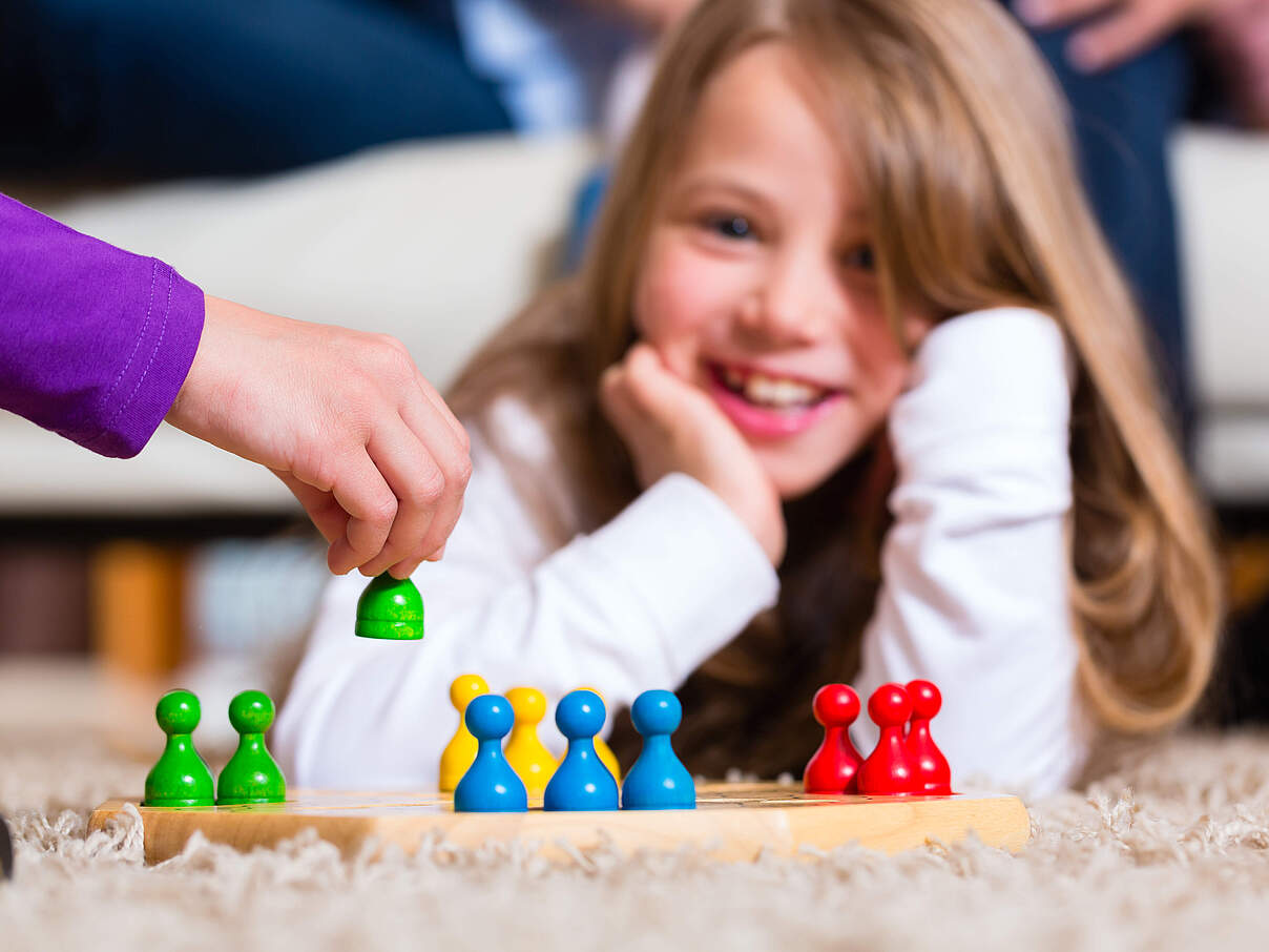 Spielbrett mit bunten Spielfiguren aus Holz © GettyImages © GettyImages