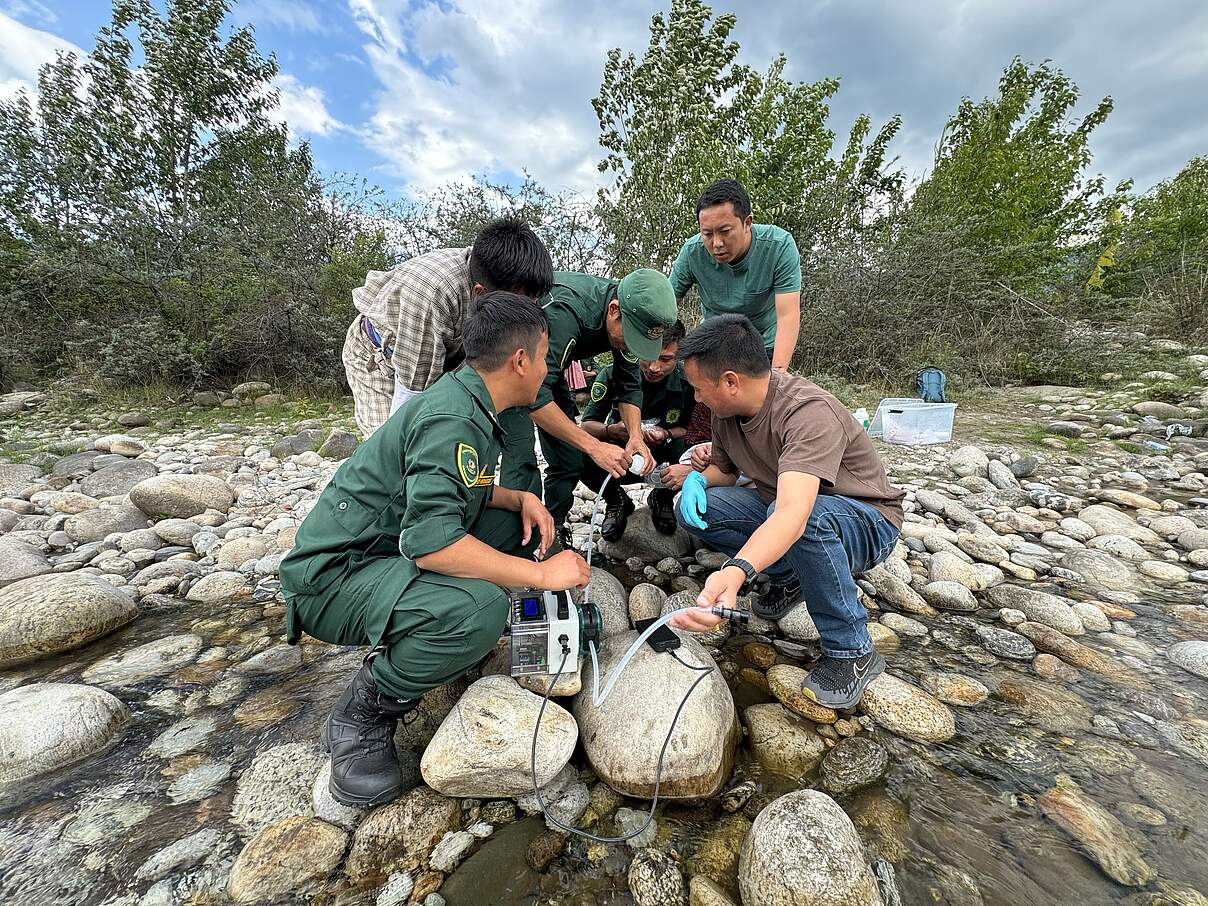 Mehrere Männer und Frauen um technische Geräte auf Felsen an Fluss