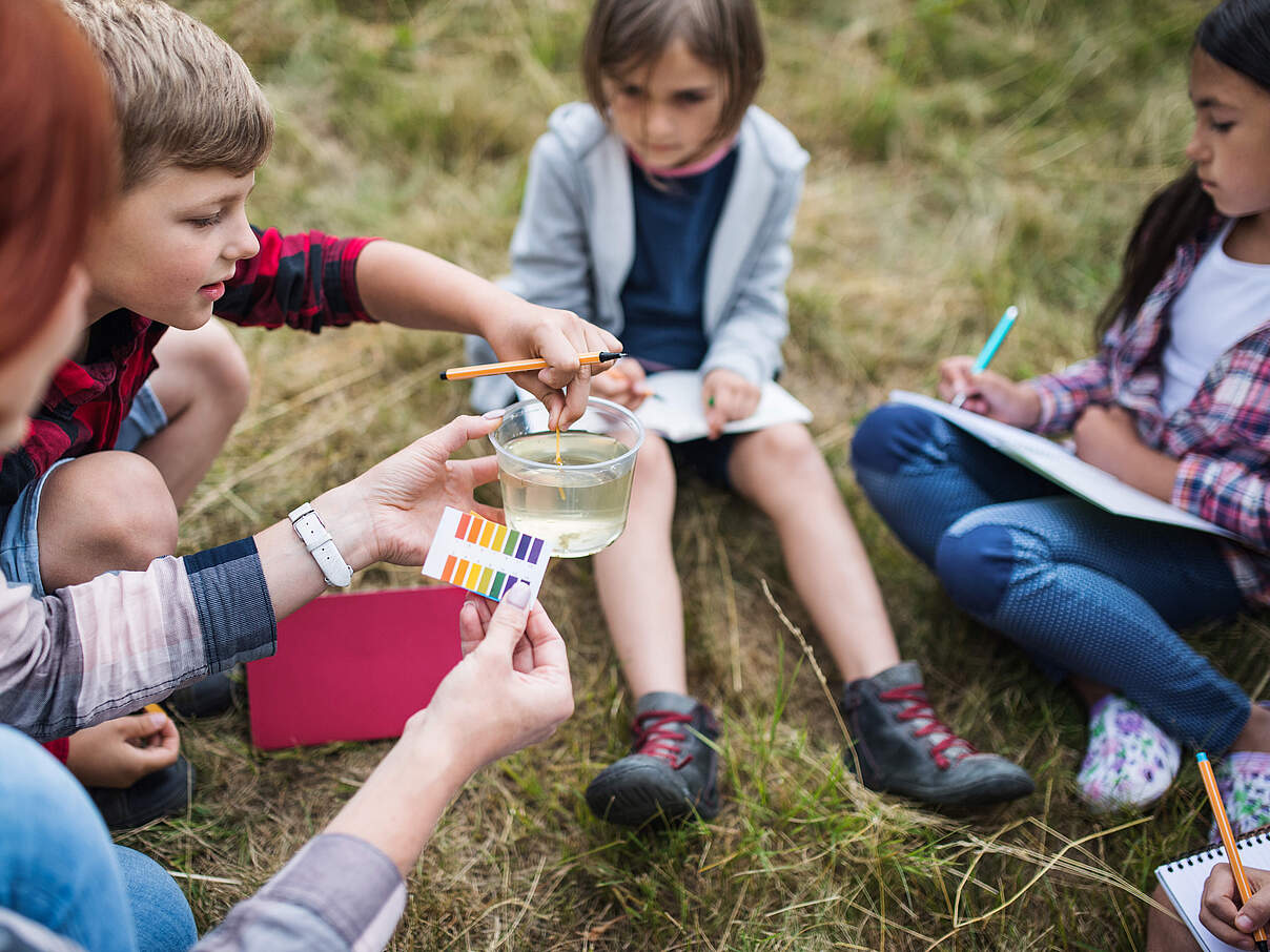 Schüler auf Exkursion testen pH-Wert des Wassers © GettyImages