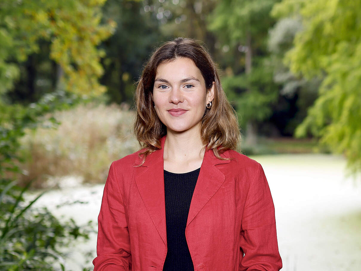 ein Portrait von Jana Beier, Projektmanagerin für nachhaltige Lieferketten beim WWF, sie schaut in die Kamera im Hintergrund grüne Natur
