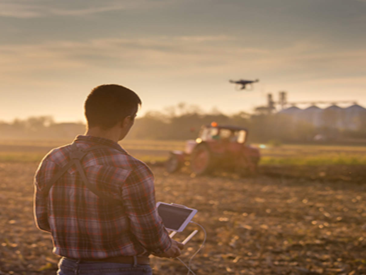 Farmer navigating drone above farmland