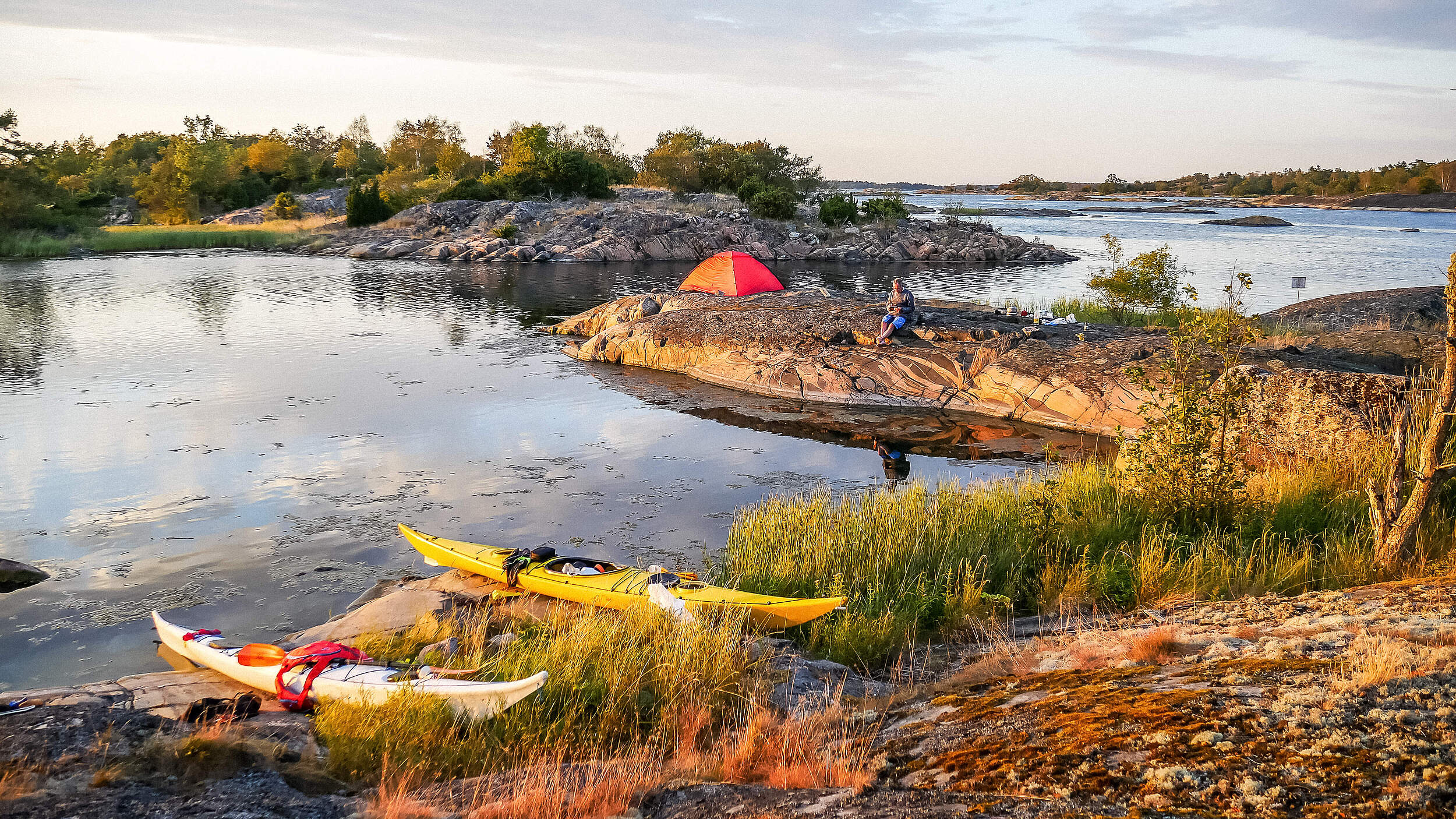 Schöne Landschaftaufnahme an einem Fluss in Schweden mit Kanus und Menschen die die Natur geniessen