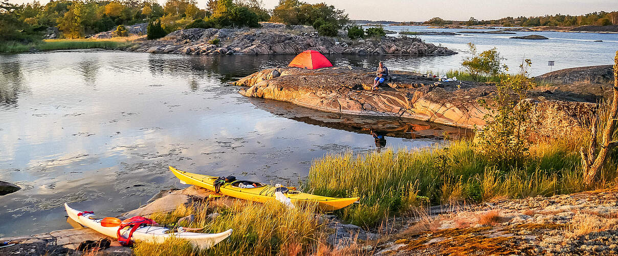 Schöne Landschaftaufnahme an einem Fluss in Schweden mit Kanus und Menschen die die Natur geniessen