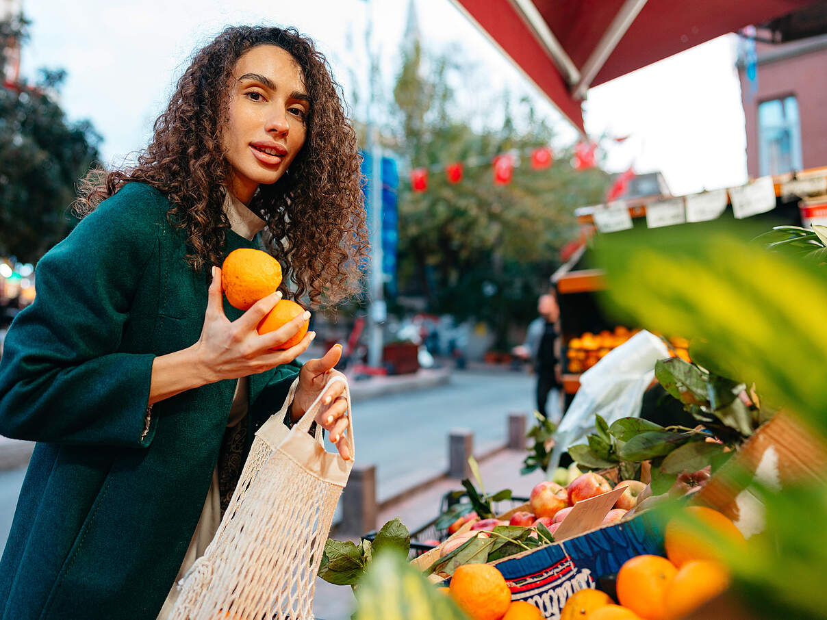 Young woman consumer choosing products to buy from local farmers market stand