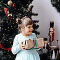 Mädchen mit einem Geschenk vor dem Weihnachtsbaum