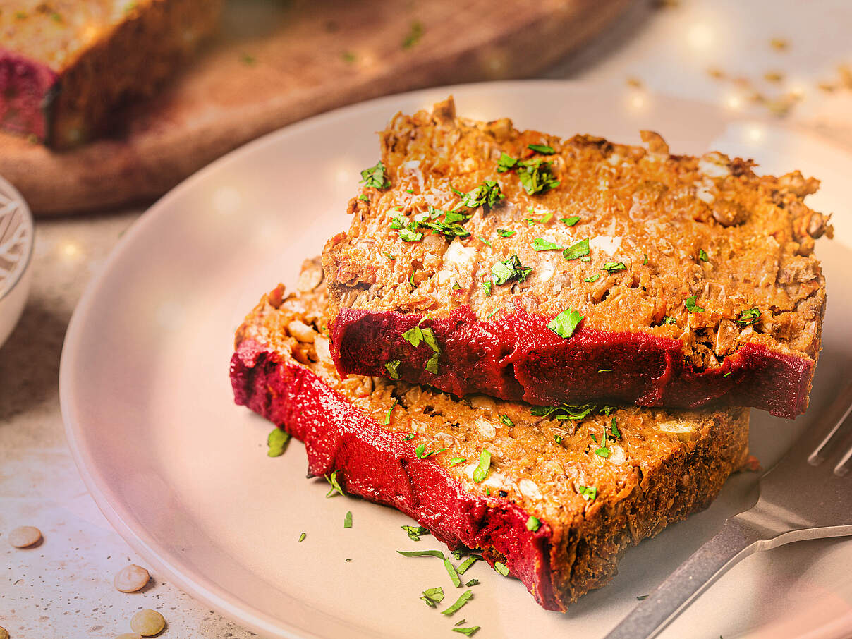 Zwei Scheiben veganen Linsen-Hackbratens festlich auf einem Teller angerichtet