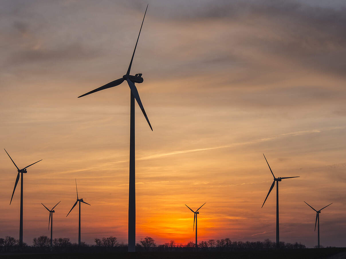 Windräder im Gegenlicht mit einem wunderschönen Sonnenuntergang in Hintergrund