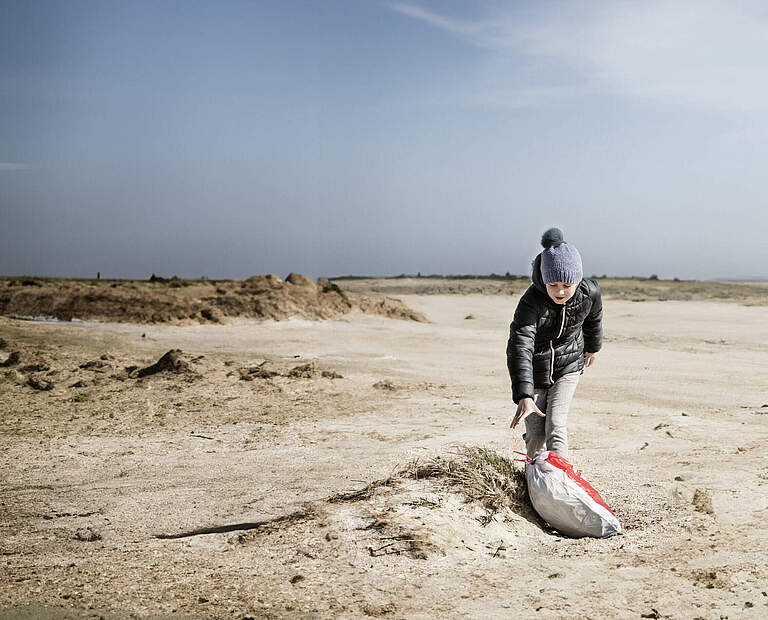 Kind sammelt Müll am Strand © Red Star