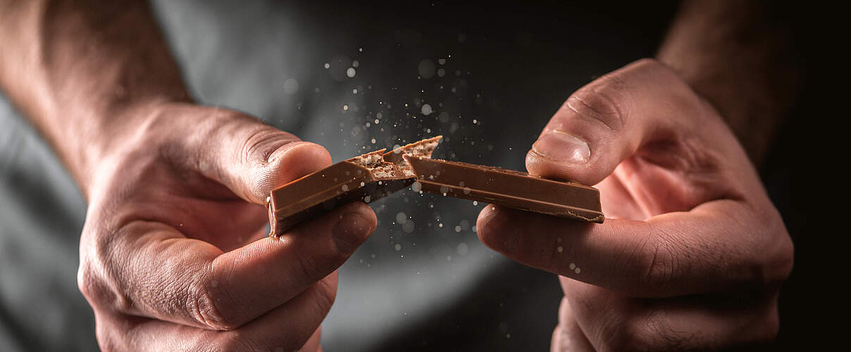 Mann bricht Schokolade