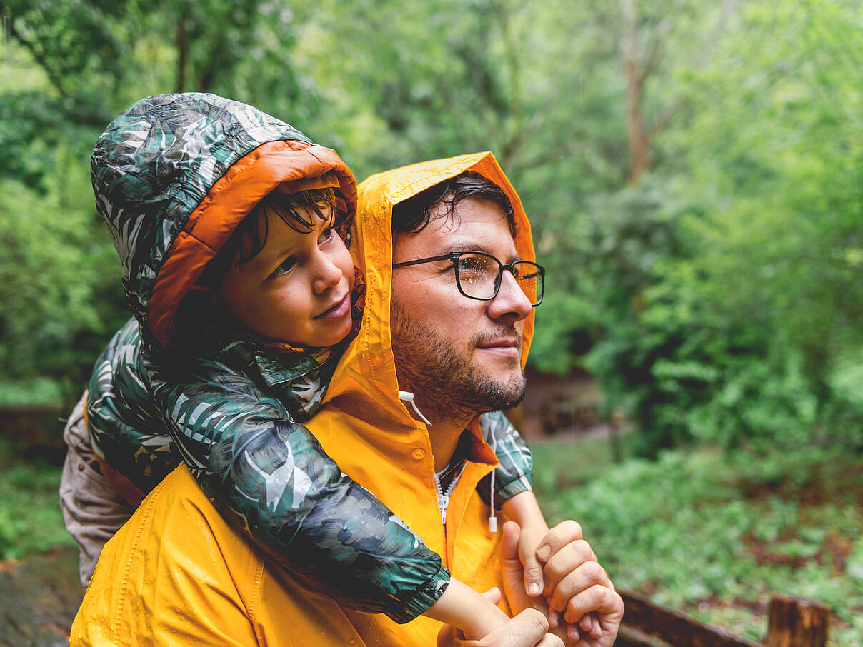 Mann und Kind bei Regen unterwegs in der Natur