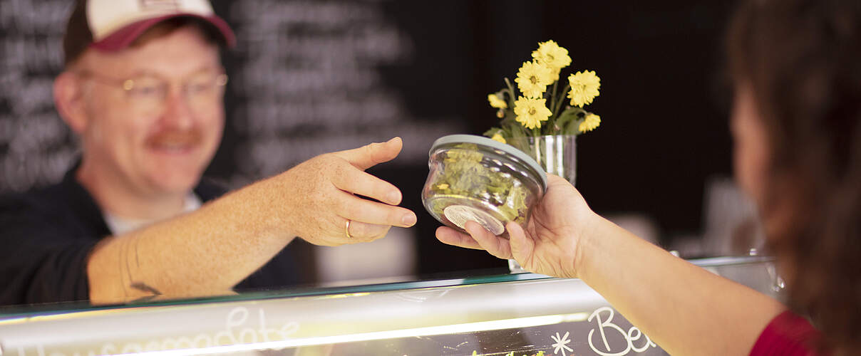 Essen wird einer Mehrwegbox über den Tresen gereicht