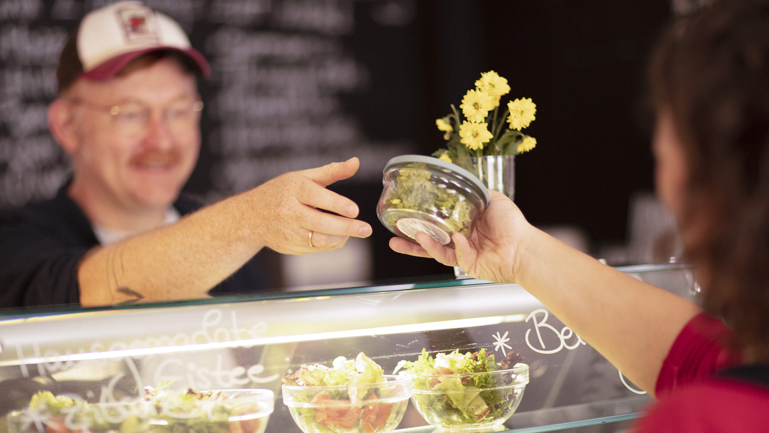 Essen wird einer Mehrwegbox über den Tresen gereicht