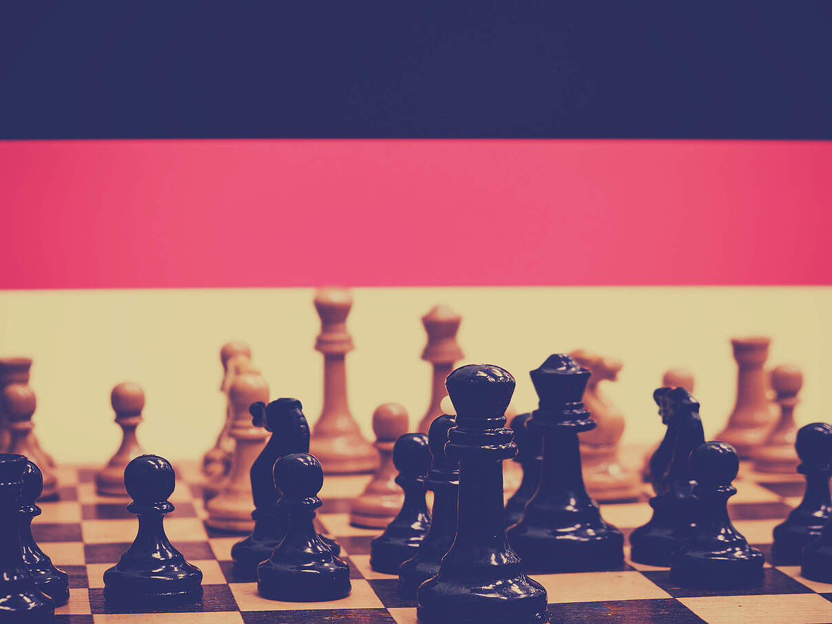 German flag on the background of a chessboard with pieces