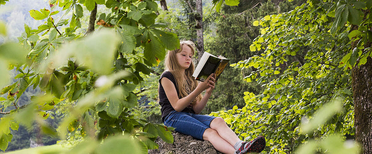 Mädchen liest im Wald ein Buch
