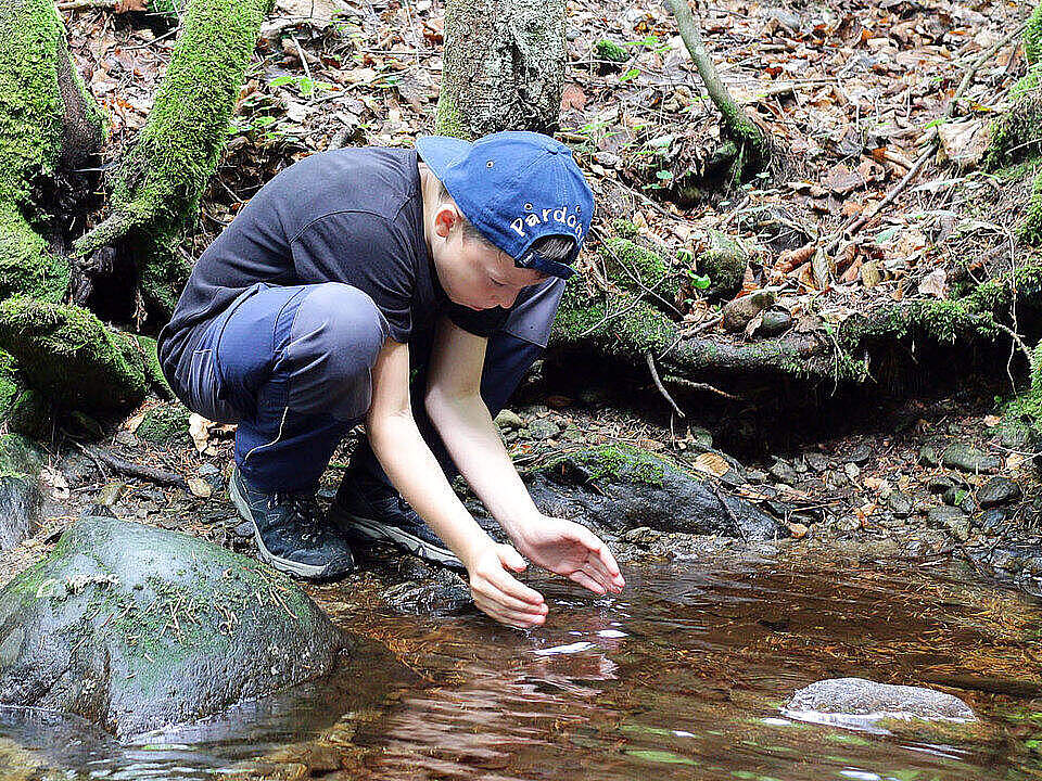 Junge an einem Bachlauf im Bayerischen Wald 