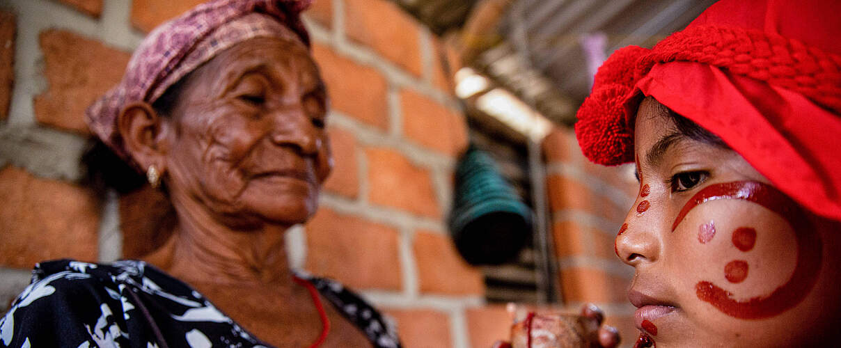 Wayuu Frau bemalt auf tradionelle Art ihre Enkelin in Kolumbien © IMAGO / SOPA Images