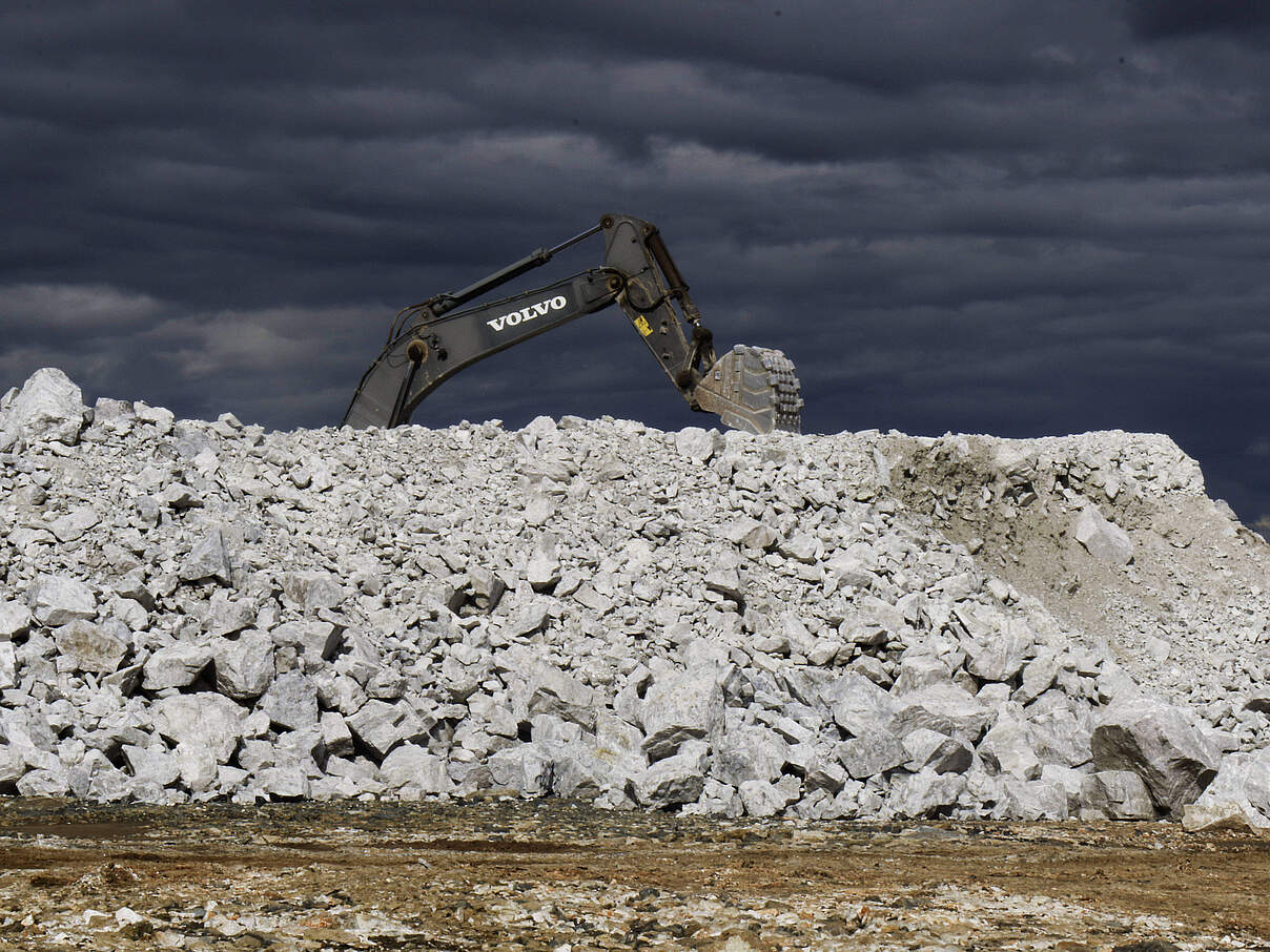 Hinter einem Geröllhaufen in einer Lithium-Mine in Simbabwe ist ein grabender Bagger zu sehen.