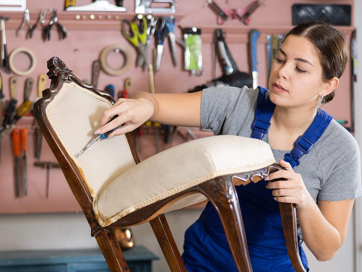 Frau restauriert einen alten Stuhl in einer Werkstatt © JackF / iStock / Getty Images