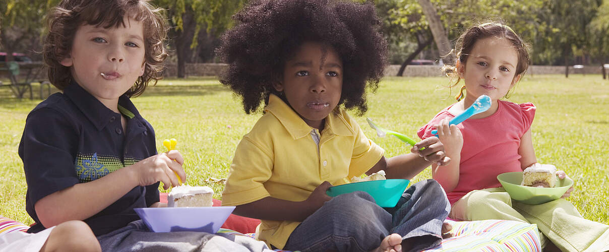 Kinder essen Kuchen im Park