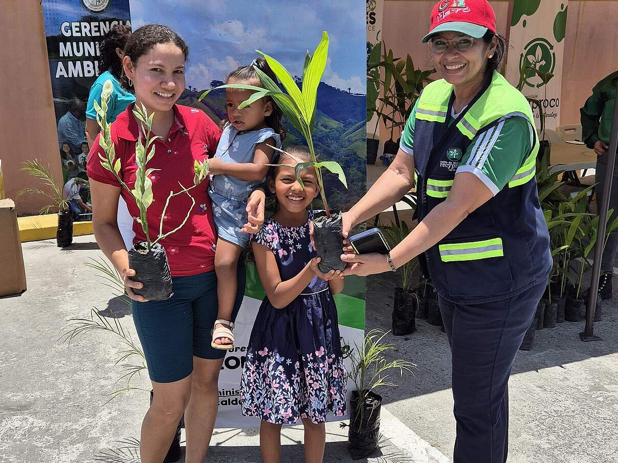 Emmy Raudales (rechts) überreicht einer Familie einen Baum im Rahmen einer Aktion zur Sensibilisierung für Umweltschutz, Recycling und den Schutz der natürlichen Ressourcen in Honduras