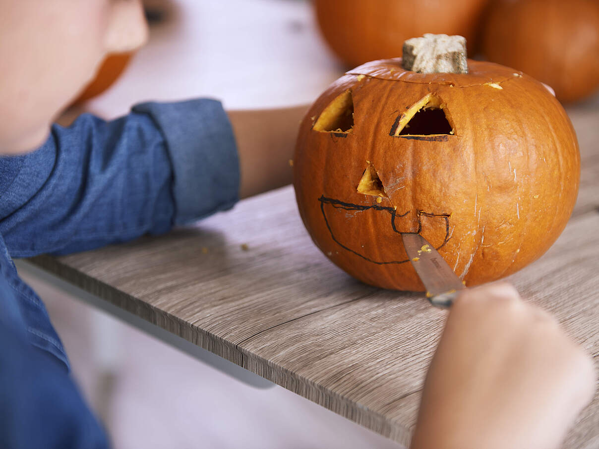 Kind schnitzt einen Kürbis