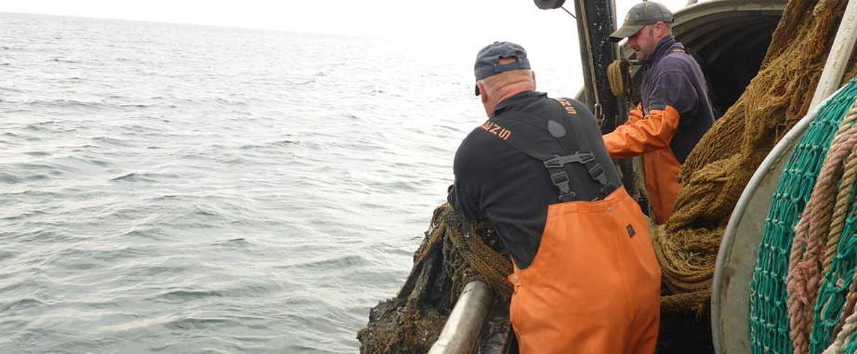 Ein fischer in einem boot mit einem netz im wasser