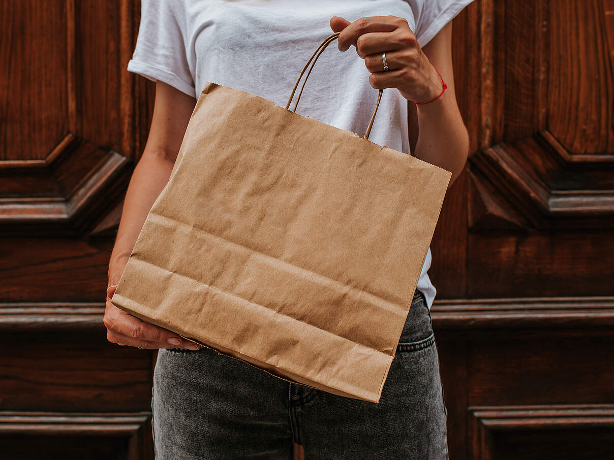 Person mit Papiertüte in der Hand