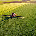 Traktor besprüht grünes Feld © oticki / iStock / Getty Images