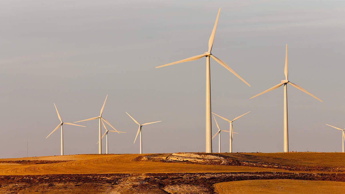 Windkrafträder auf einem Hügel von der Abendsonne in Spanien beschienen