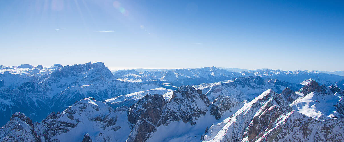 Landschaftsbild der Dolomiten im Winter bei strahlendem Sonnenschein.