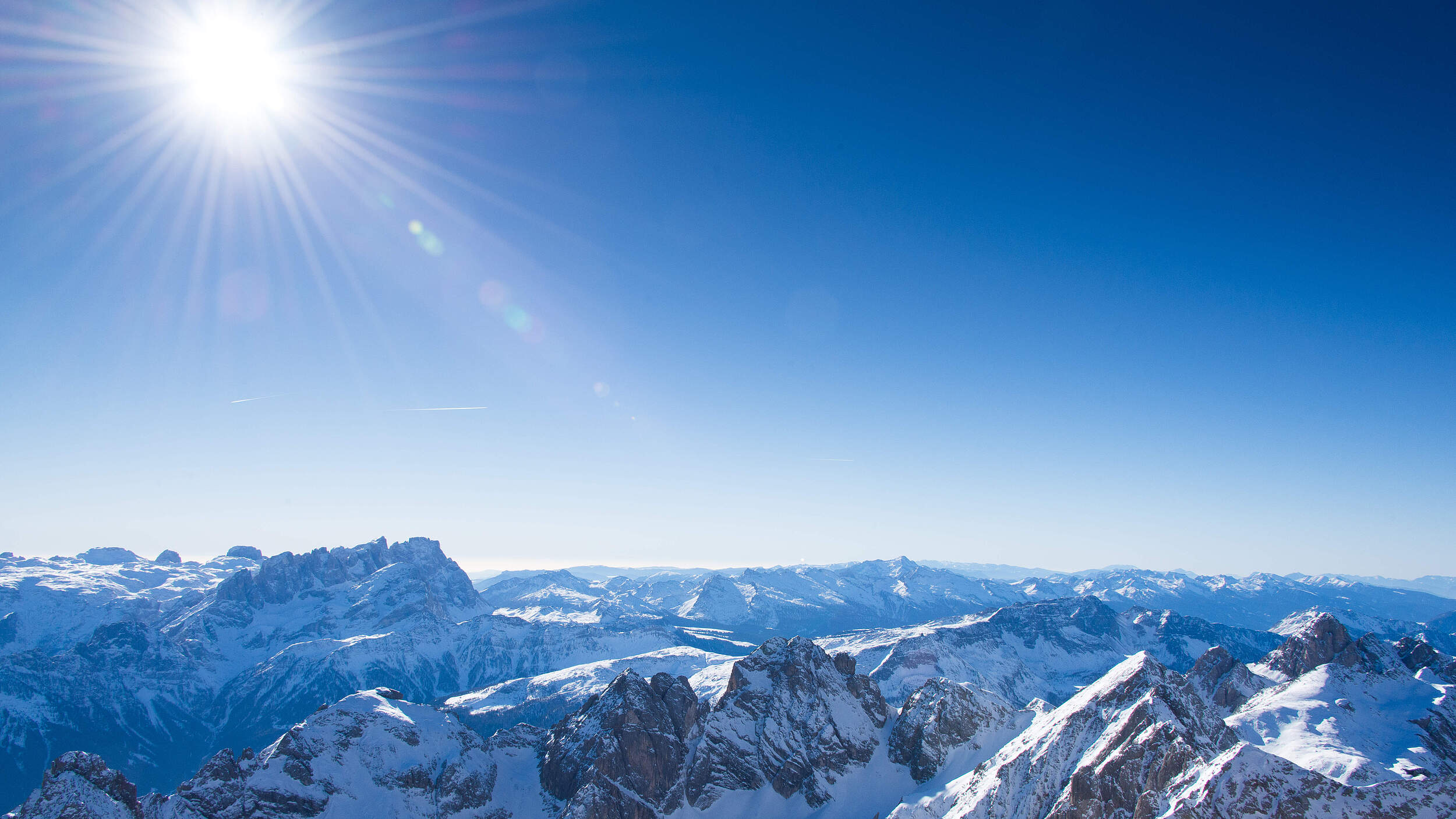 Landschaftsbild der Dolomiten im Winter bei strahlendem Sonnenschein.