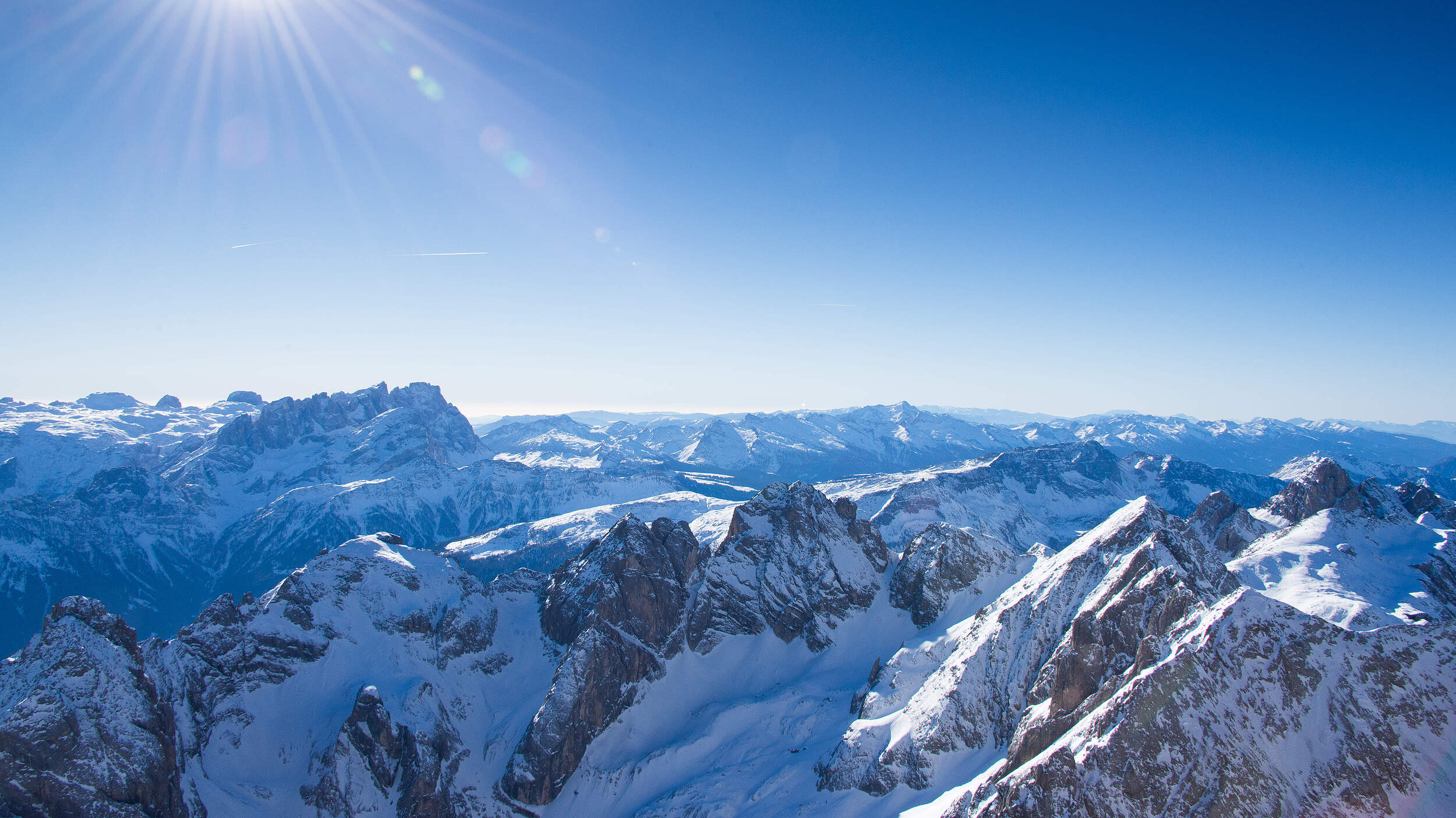 Landschaftsbild der Dolomiten im Winter bei strahlendem Sonnenschein.
