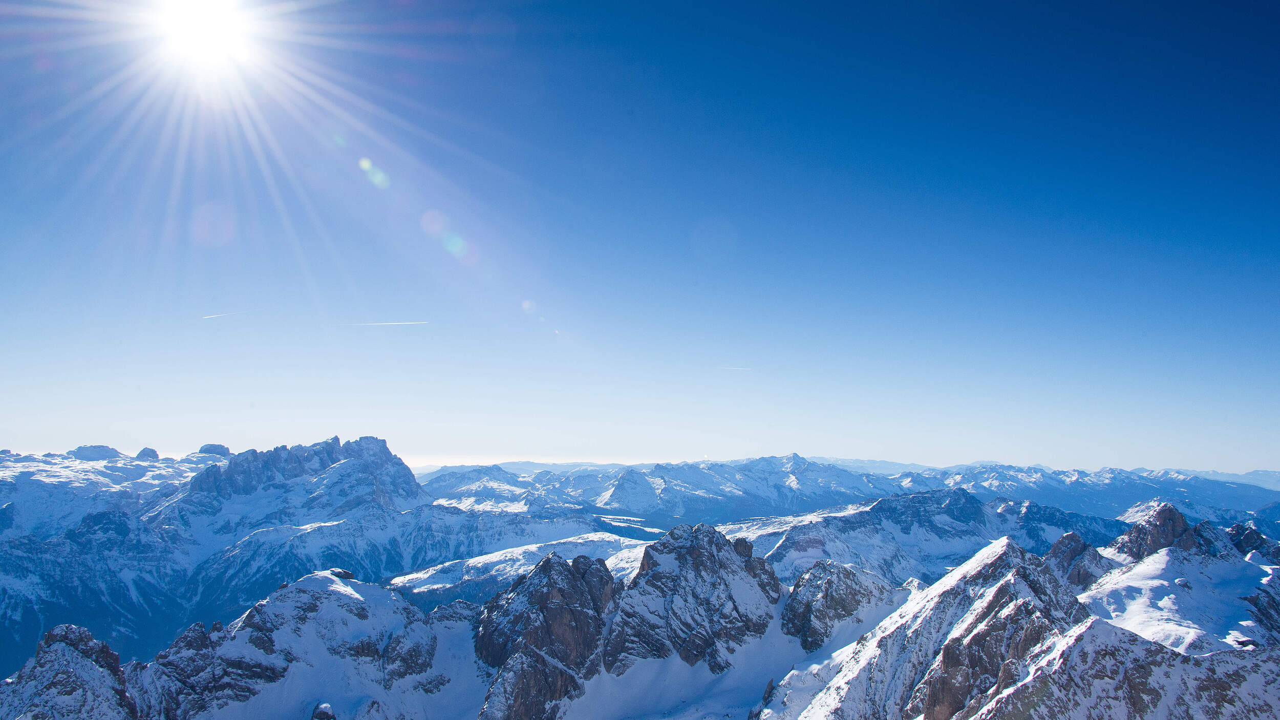Landschaftsbild der Dolomiten im Winter bei strahlendem Sonnenschein.