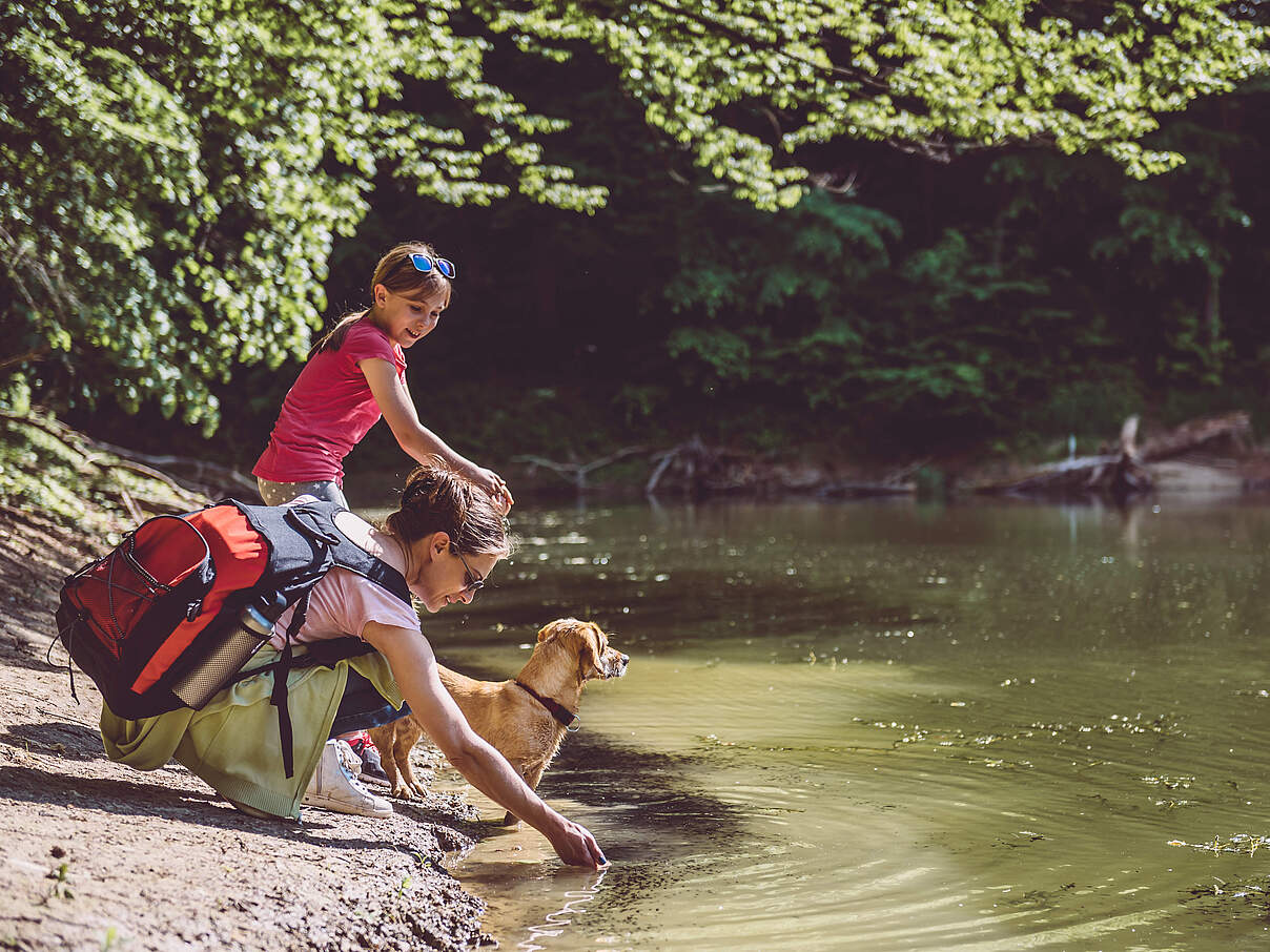 Frau mit Kind und Hund am Wasser